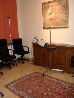 Zimmer mit hellen Wänden mit Gemälde, schwarze Chefsessel, Rotlicht, Infusionsständer, orientalischer Teppich, Echtholz-Sideboard mit Zeitschriften